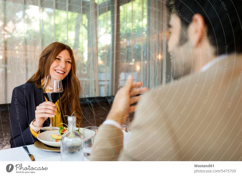 Smiling woman with glass of red wine looking at man in a restaurant smiling smile restaurants couple twosomes partnership couples Red Wine Red Wines drinking