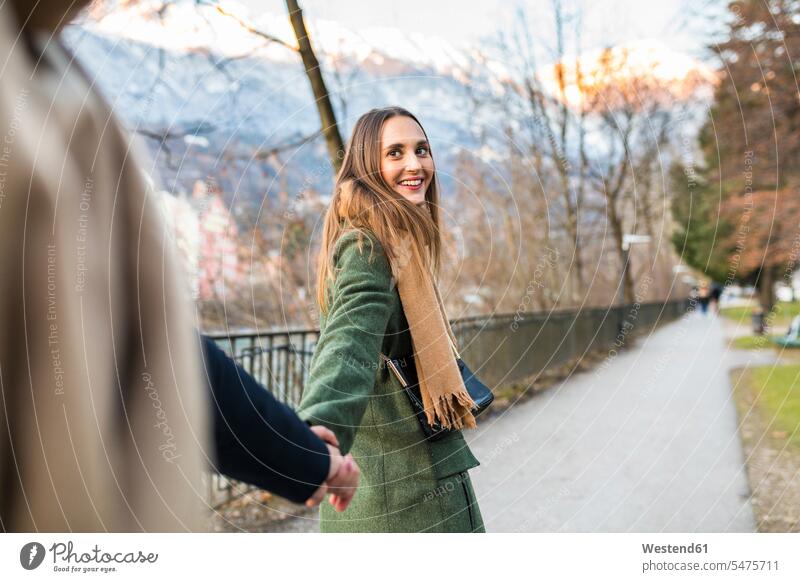 Austria, Innsbruck, portrait of happy young woman strolling hand in hand with her boyfriend at winter time portraits Wintertime Winter time Boyfriends happiness