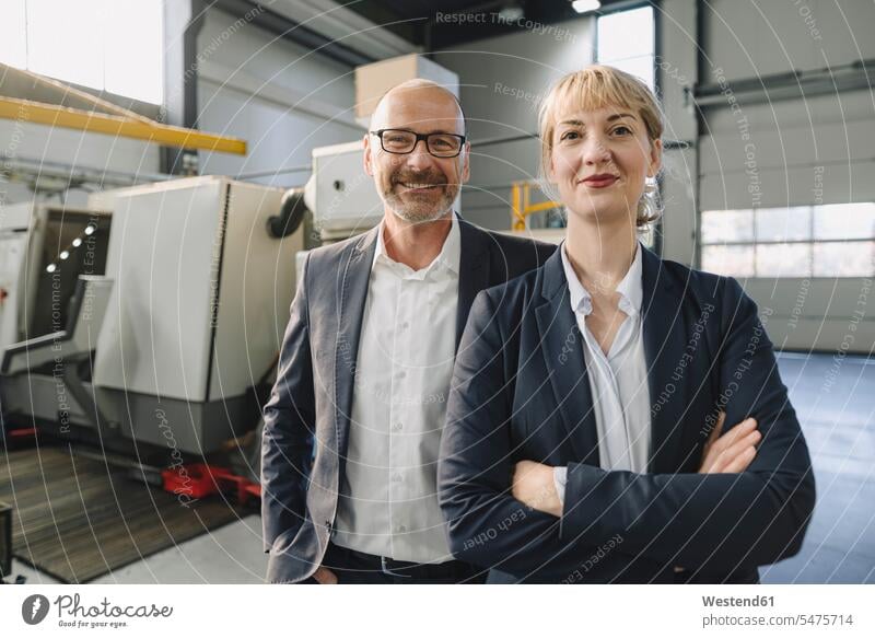 Portrait of confident businessman and businesswoman in a factory business life business world business person businesspeople associate associates