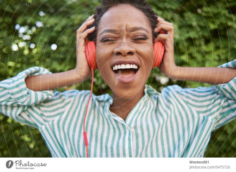 Portrait of singing young woman with headphones headset females women portrait portraits Adults grown-ups grownups adult people persons human being humans