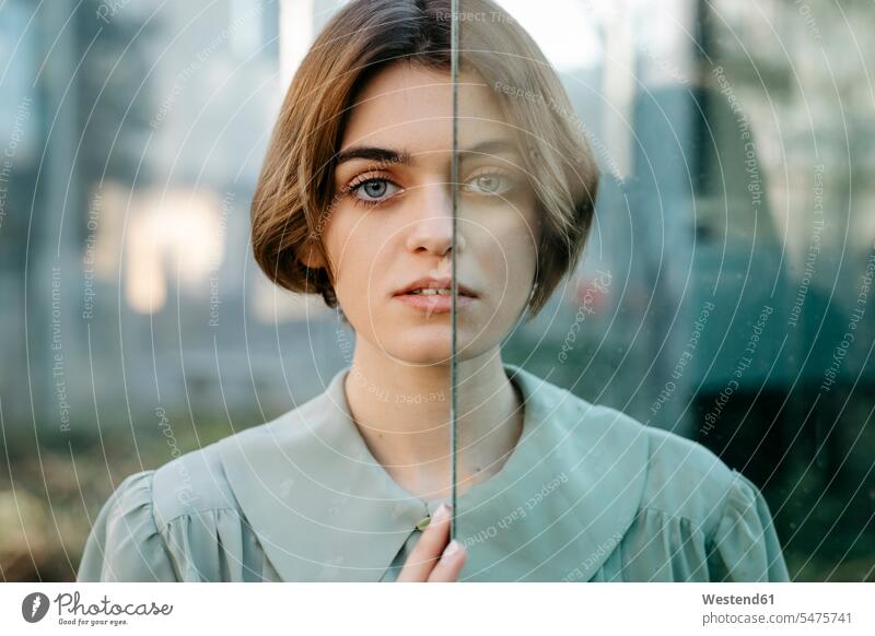 Portrait of woman with half of her face behind a glass windows glass panes shirts Retro retro revival Retro Styled Retro-Styled diffident reluctance reluctant