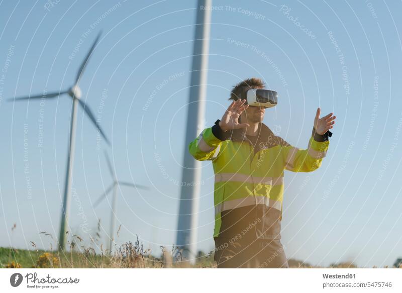 Engineer standing in a field at a wind farm wearing VR glasses specs Eye Glasses spectacles Eyeglasses virtual wind park Field Fields farmland engineer