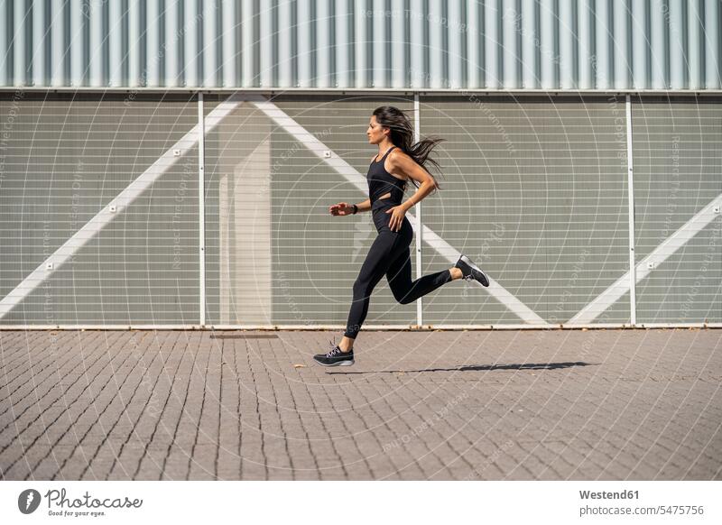 Young female jogger running in front of a wall free time leisure time Recreational Activities Recreational Activity Recreational Pursuits leisure time sports