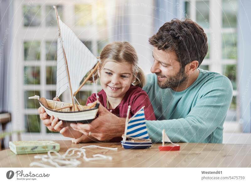 Happy father and daughter playing with model boat at home Toy Boat daughters pa fathers daddy dads papa happiness happy child children family families people