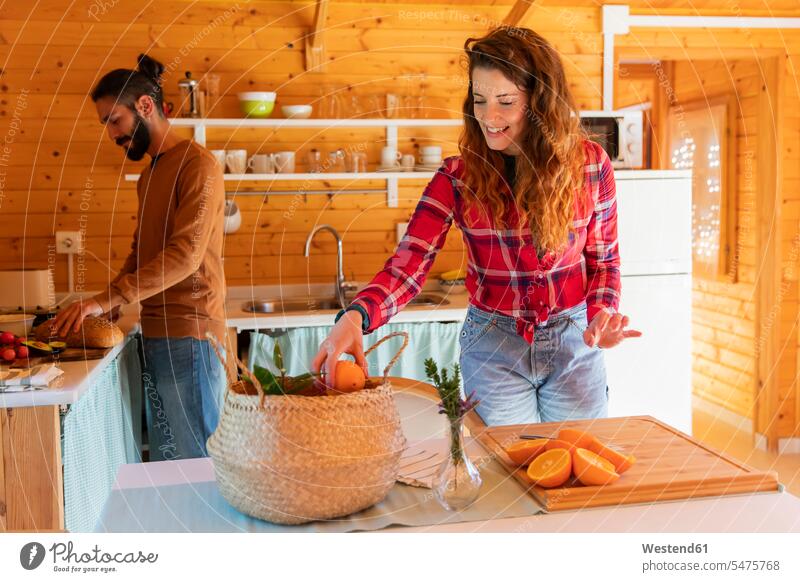 Woman with boyfriend in a wooden cabin preparing oranges touristic tourists baskets smile cut delight enjoyment Pleasant pleasure indulgence indulging savoring