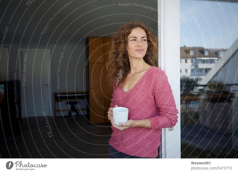 Beautiful woman holding coffee cup while leaning on door at home color image colour image day daylight shot daylight shots day shots daytime Home Interior
