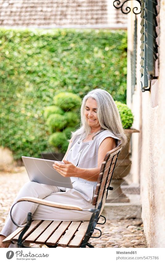 Woman with long grey hair sitting on bench at country house using tablet digitizer Tablet Computer Tablet PC Tablet Computers iPad Digital Tablet