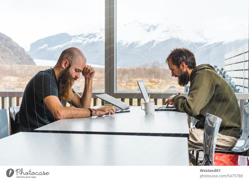 Island, two Hipsters sitting at table in a coffee shop Table Tables cafe Seated looking down Internet The Internet Wifi Wi-Fi wireless internet WLan