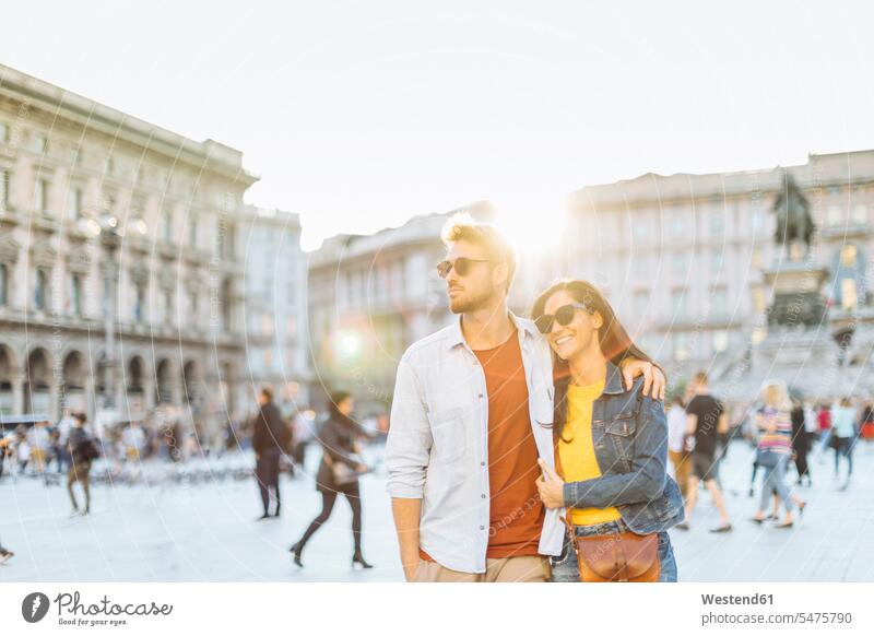 Happy young couple on a square in the city at sunset, Milan, Italy touristic tourists Eye Glasses Eyeglasses specs spectacles Pair Of Sunglasses sun glasses