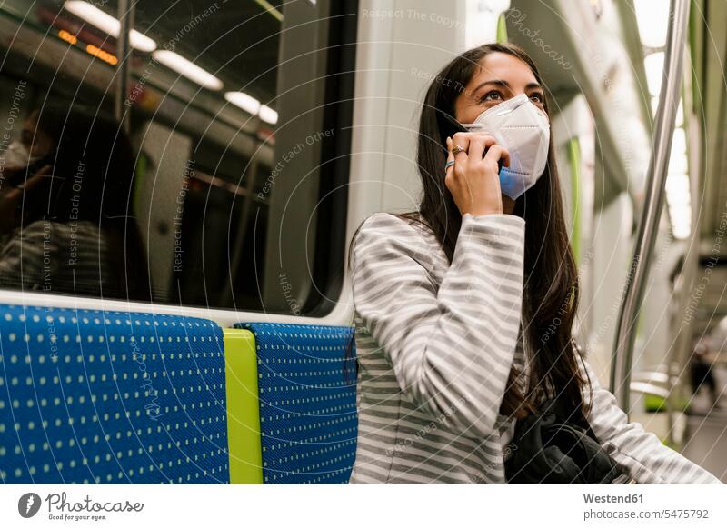 Woman looking away while talking on smart phone in metro train color image colour image Spain sitting Seated infection infected Infectious Disease
