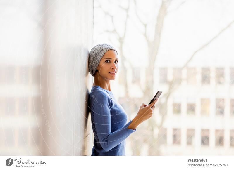 Portrait of young woman with cell phone in front of window windows portrait portraits Smartphone iPhone Smartphones females women mobile phone mobiles