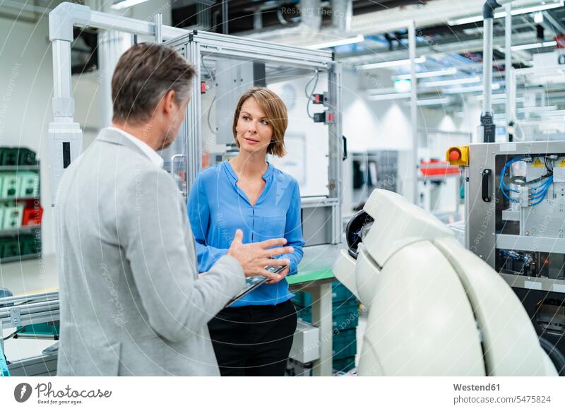 Businessman with tablet and woman talking at assembly robot in a factory human human being human beings humans person persons caucasian appearance