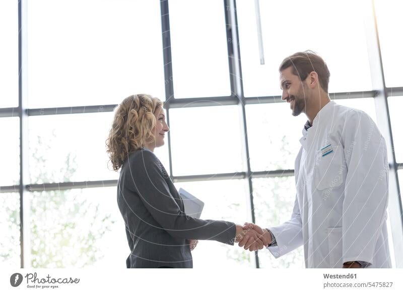 Businesswoman and doctor shaking hands in hospital human human being human beings humans person persons caucasian appearance caucasian ethnicity european 2
