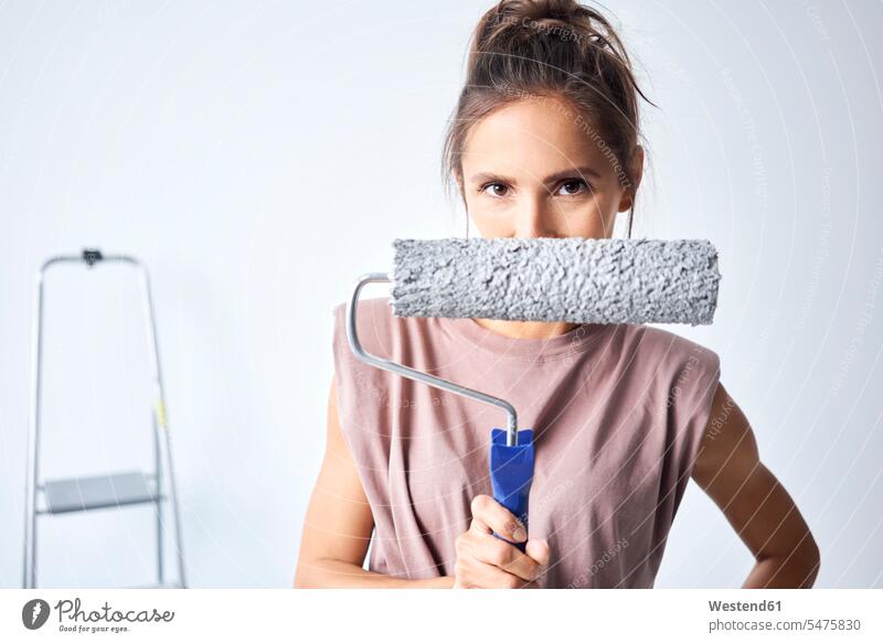 Young woman holding paint roller while standing at home color image colour image indoors indoor shot indoor shots interior interior view Interiors day