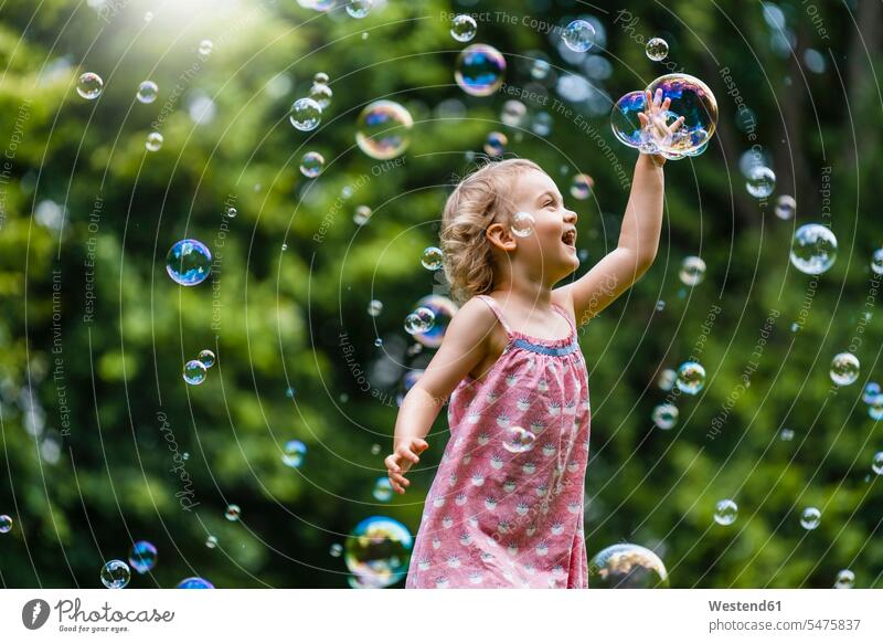 Cheerful girl amidst bubbles at park color image colour image outdoors location shots outdoor shot outdoor shots day daylight shot daylight shots day shots
