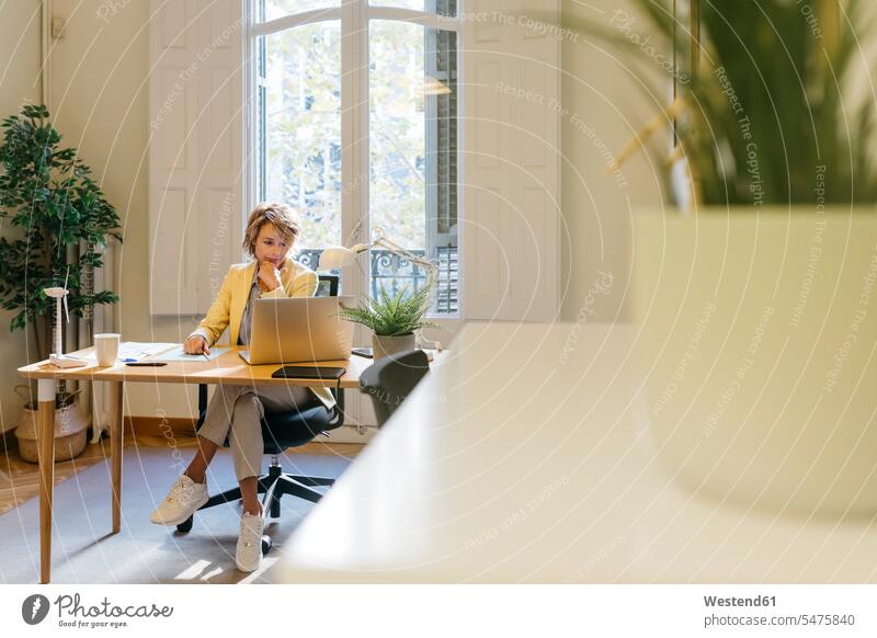 Female engineer working on laptop while sitting in office color image colour image indoors indoor shot indoor shots interior interior view Interiors day