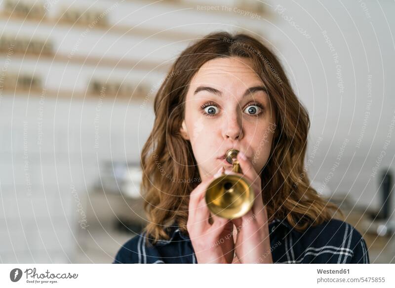 Young woman blowing toy trumpet in her coffee shop human human being human beings humans person persons caucasian appearance caucasian ethnicity european 1