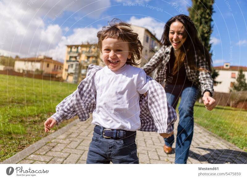 Mother running behind happy toddler son on a path trail paths sons manchild manchildren mother mommy mothers mummy mama happiness family families people persons