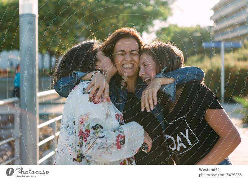 Cheerful loving mother embracing daughters while standing outdoors color image colour image Portugal leisure activity leisure activities free time leisure time