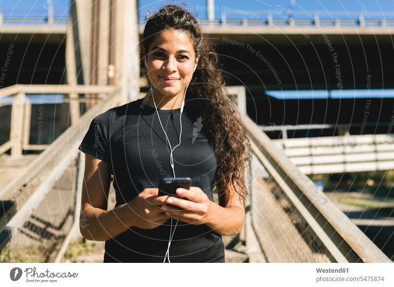 Portrait of sporty young woman having a break listening to music sportive sporting athletic females women portrait portraits hearing sports Adults grown-ups