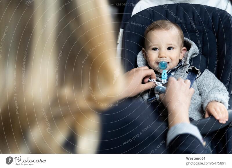 Portrait of baby boy with pacifier in strollerwatching his mother Italy baby boys male motherhood attention attentive paying attention Selective focus