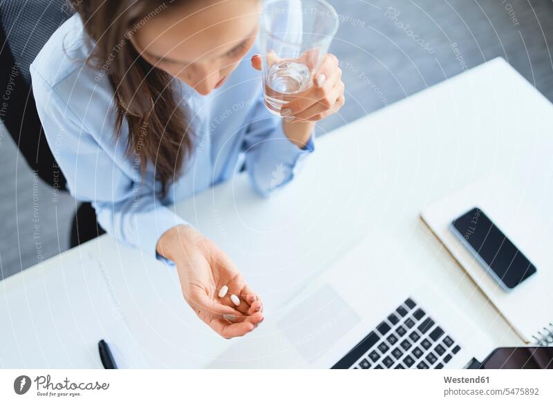Overhead view of woman taking painkillers while sitting on office human human being human beings humans person persons adult grown-up grown-ups grownup grownups