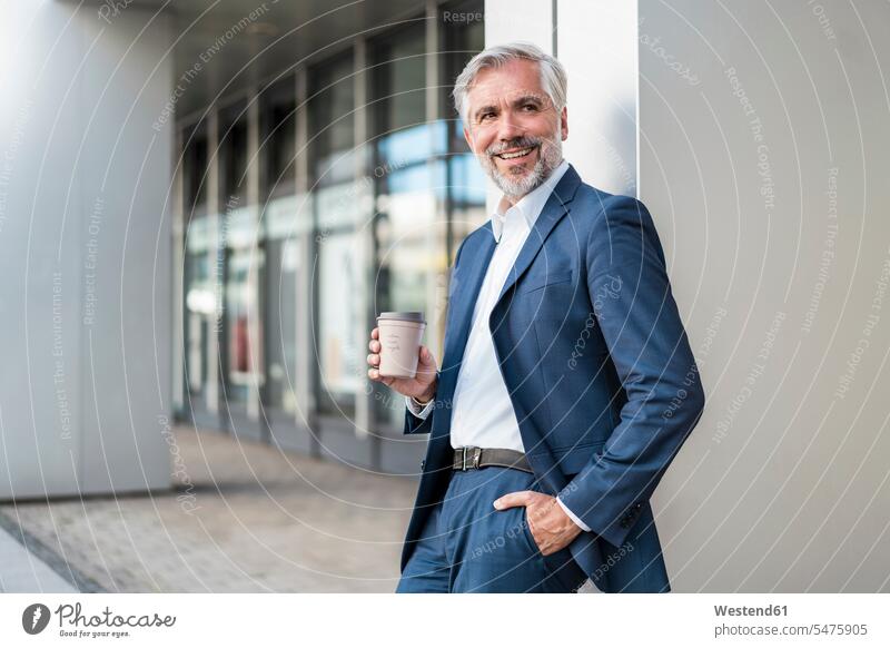 Smiling mature businessman with takeaway coffee in the city human human being human beings humans person persons caucasian appearance caucasian ethnicity