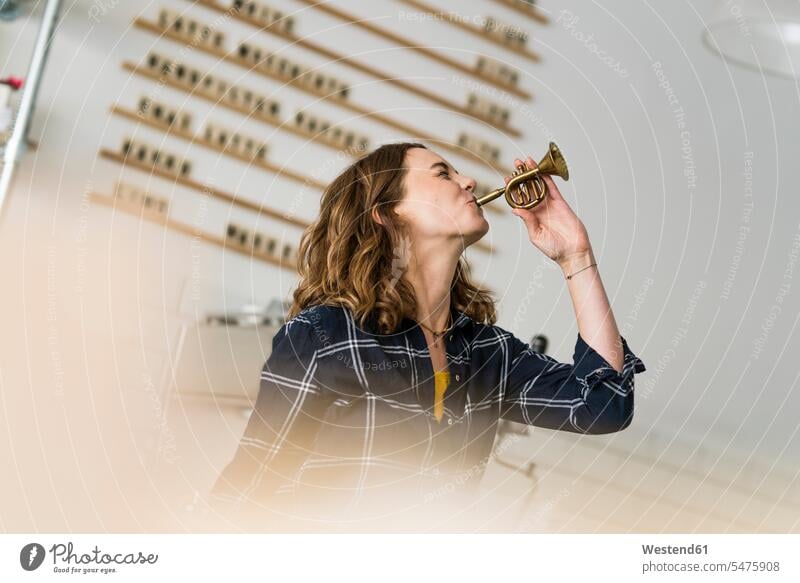Young woman blowing toy trumpet in her coffee shop human human being human beings humans person persons caucasian appearance caucasian ethnicity european 1