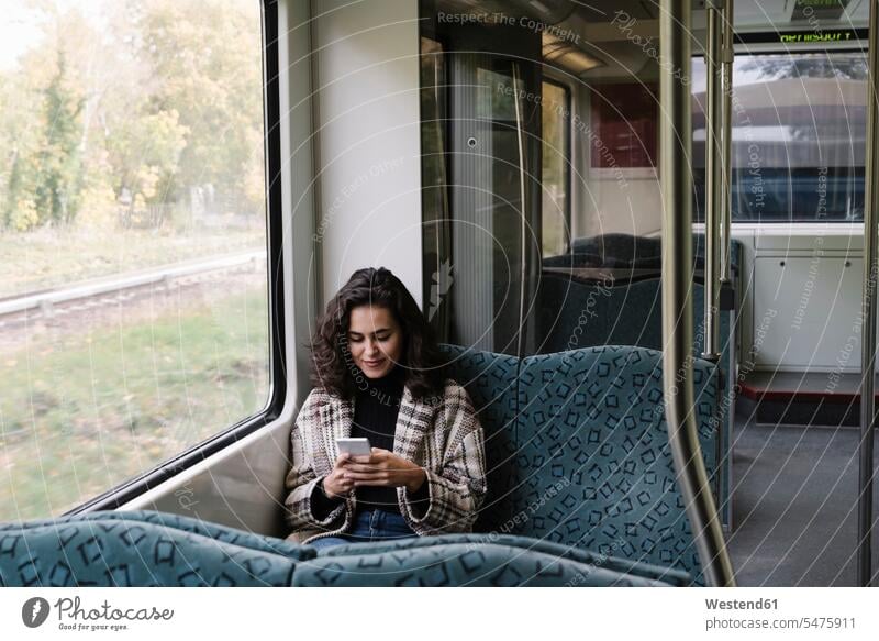 Young woman using smartphone on a subway windows pane panes window glass window glasses Window Pane windowpanes transport railroad railroads Railways