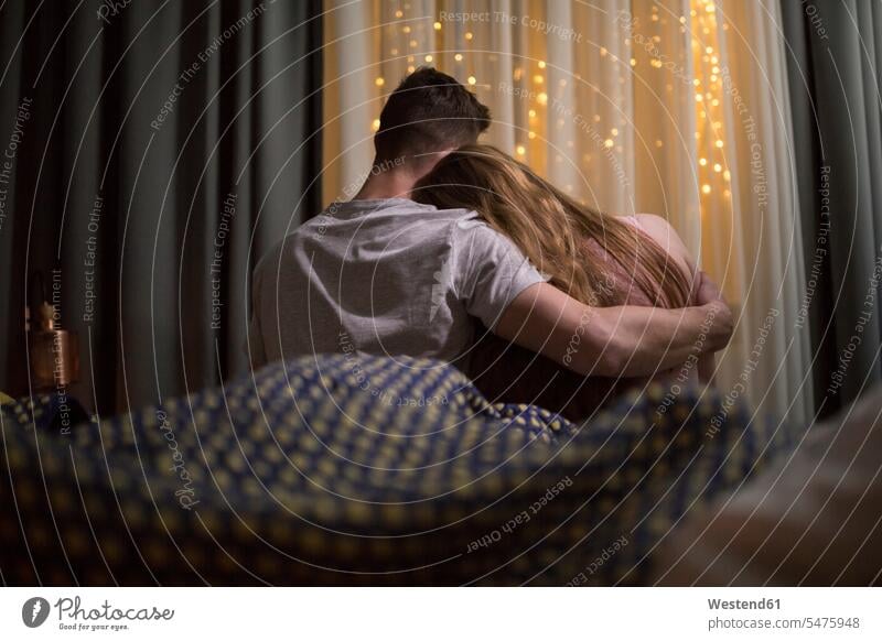 Romantic young couple sitting on bed beds Seated romantic lyrical Romance twosomes partnership couples people persons human being humans human beings Curtain