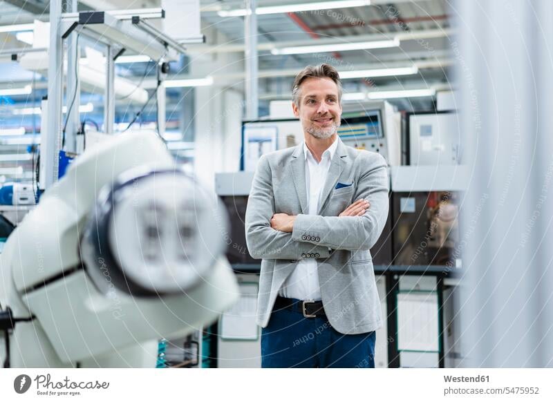 Portrait of confident businessman at assembly robot in a factory Occupation Work job jobs profession professional occupation business life business world