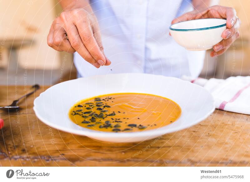 Woman putting sesame seed in soup while standing at table color image colour image indoors indoor shot indoor shots interior interior view Interiors day