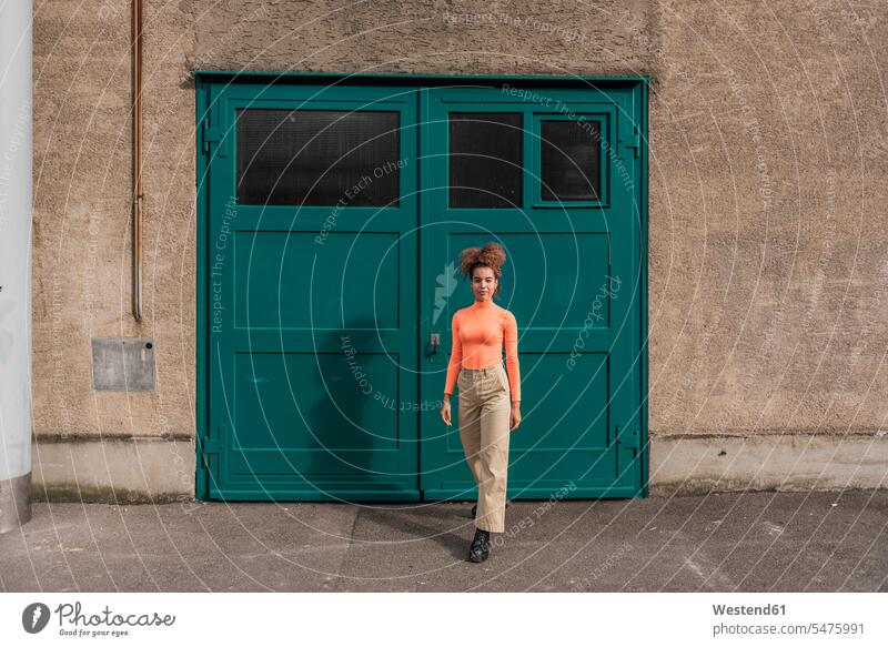 Young woman walking against green door color image colour image outdoors location shots outdoor shot outdoor shots day daylight shot daylight shots day shots
