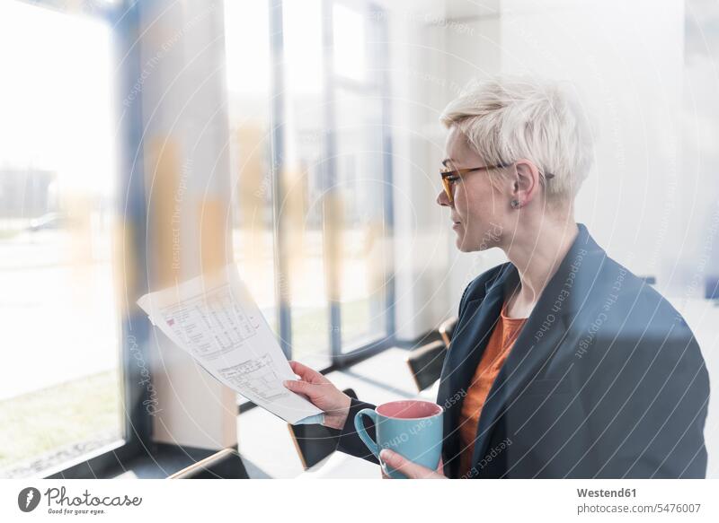 Businesswoman reading document in office businesswoman businesswomen business woman business women paper documents papers Office Offices business people