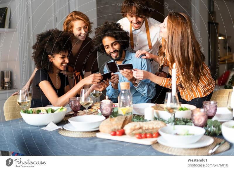Friends sitting at dining table, looking at photographs Seated photos Quality Time Dining Table Dinner Table Dining Tables friends eyeing image images picture