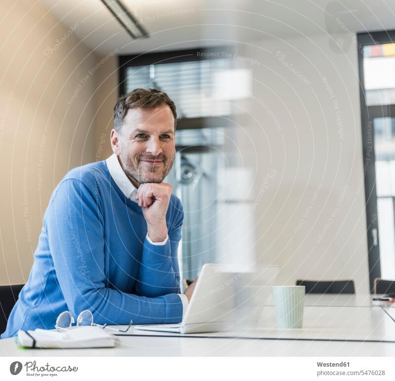 Portrait of smiling businessman with laptop in office Businessman Business man Businessmen Business men portrait portraits Laptop Computers laptops notebook