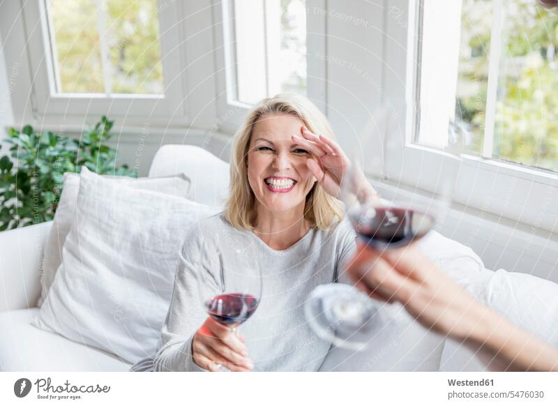 Portrait of laughing blond mature woman toasting with red wine at home blond hair blonde hair Red Wine Red Wines females women Laughter portrait portraits
