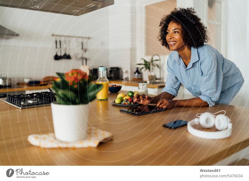 Woman using digital tablet and having a healthy breakfast in her kitchen Breakfast smiling smile Fruit Fruits standing use morning in the morning