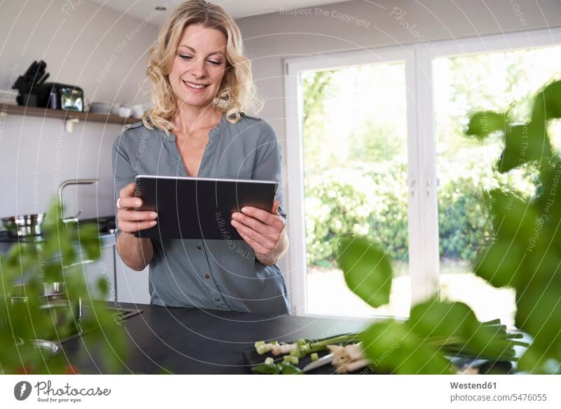 Smiling woman using tablet in kitchen smiling smile digitizer Tablet Computer Tablet PC Tablet Computers iPad Digital Tablet digital tablets domestic kitchen