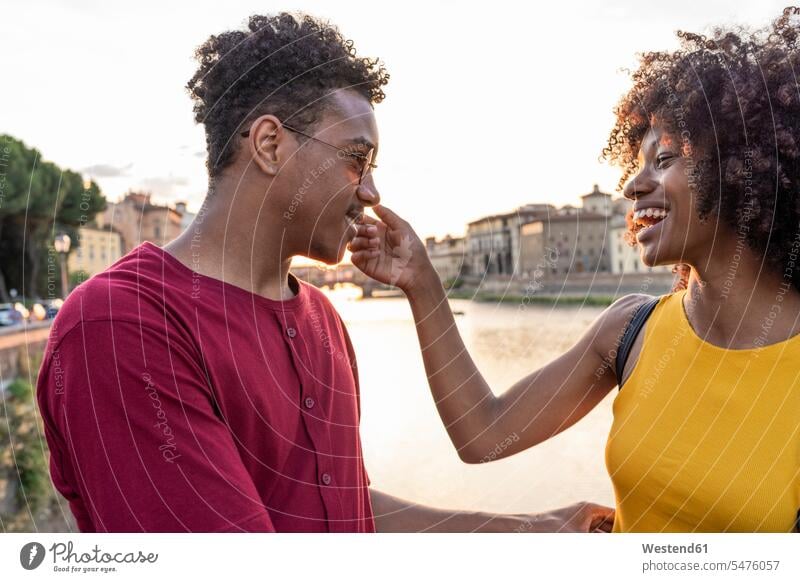 Happy young tourist couple at river Arno at sunset, Florence, Italy human human being human beings humans person persons African black black ethnicity coloured