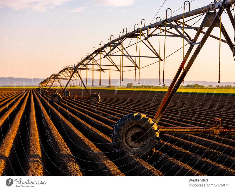 Irrigation equipment kept on ploughed field during sunset color image colour image outdoors location shots outdoor shot outdoor shots sunsets sundown atmosphere