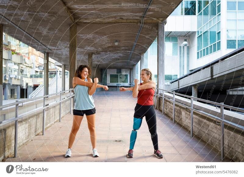 Sportswoman with prosthetic leg exercising with friend while standing on bridge color image colour image outdoors location shots outdoor shot outdoor shots day