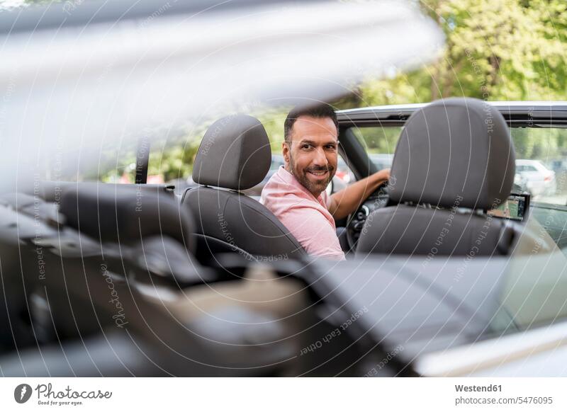 Man sitting in car with closing convertible top motorist driver casual leisure wear casual clothing casual wear casual clothes Casual Attire wealth affluence