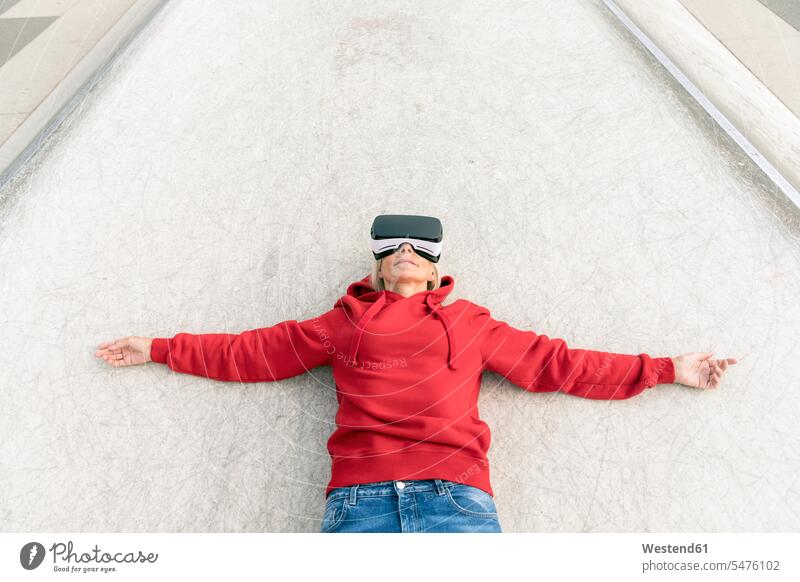 Senior woman lying on the ground wearing VR glasses specs Eye Glasses spectacles Eyeglasses laying down lie lying down land floor virtual females women Adults