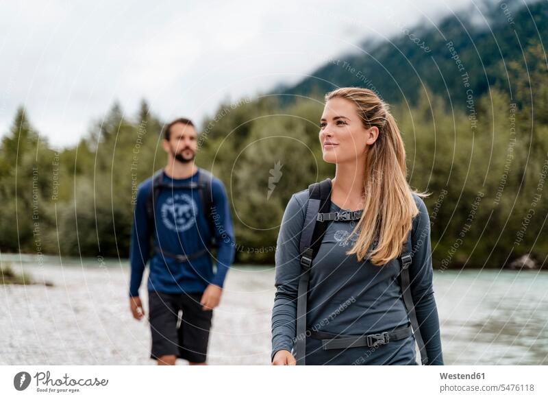 Young couple on a hiking trip at riverside, Vorderriss, Bavaria, Germany touristic tourists back-pack back-packs backpacks rucksack rucksacks go going walk