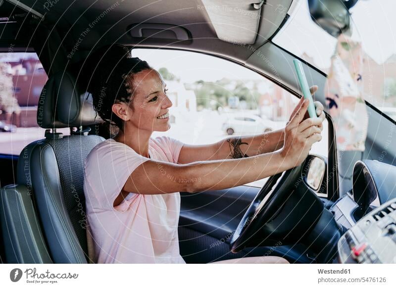 Smiling woman taking selfie while sitting in car on sunny day color image colour image Spain daylight shot daylight shots day shots daytime leisure activity
