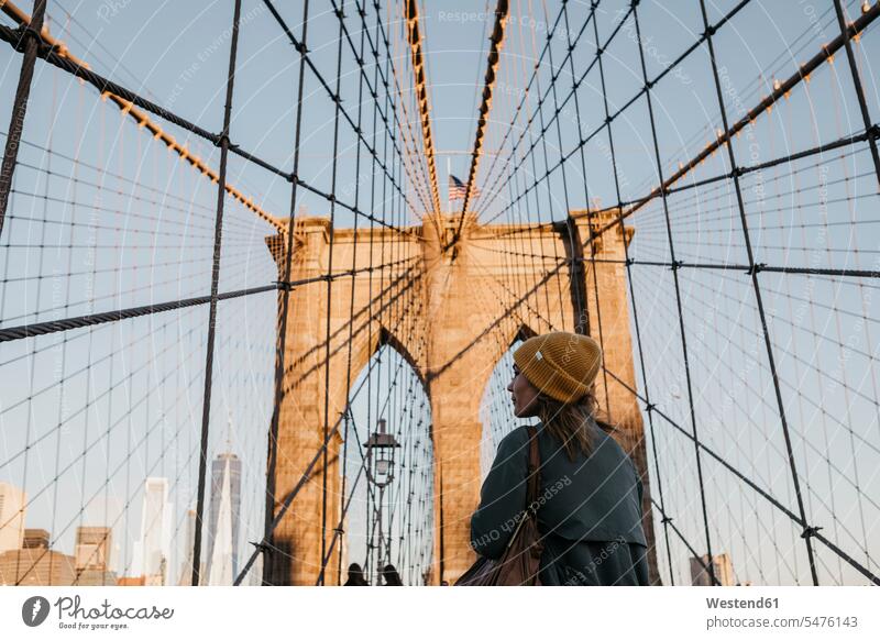 USA, New York, New York City, female tourist on Brooklyn Bridge in the morning light discovering Traveller Travellers Travelers woman females women walking