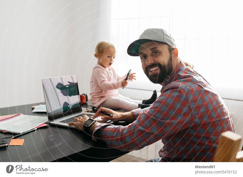 Father working from home, using laptop with his gaughter sitting on the desk, playing working at home Work From Home Smartphone iPhone Smartphones father pa