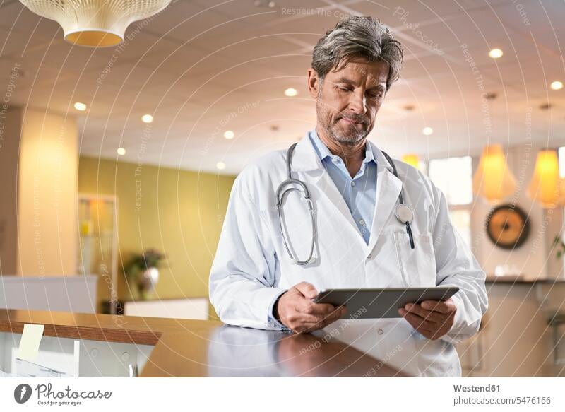 Doctor using tablet at reception in his medical practice human human being human beings humans person persons caucasian appearance caucasian ethnicity european