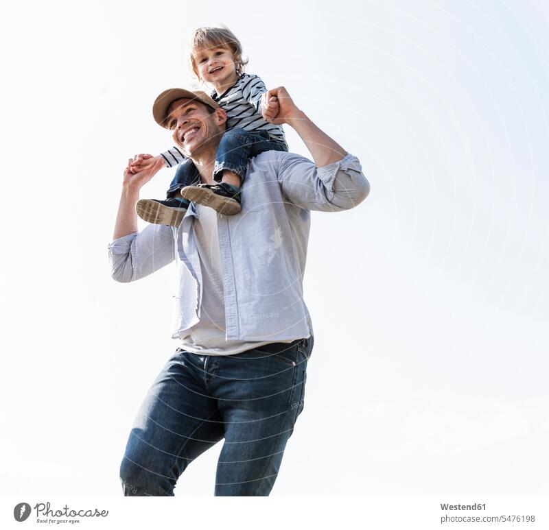Happy father carrying son on his shoulders holding bonding carefree confidence confident togetherness childhood on shoulders Quality Time boy boys males
